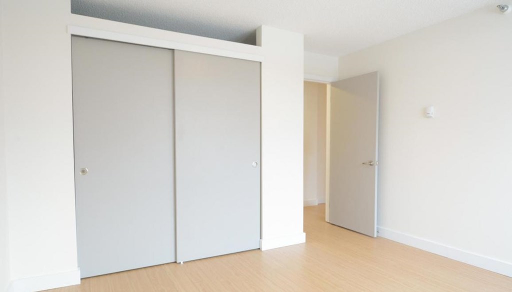 A room with two white doors and a wooden floor.